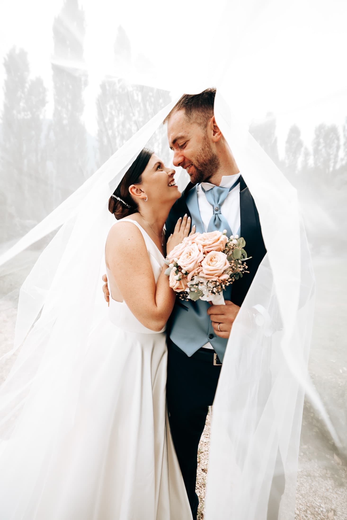 Bride and groom under the veil with her bouquet
