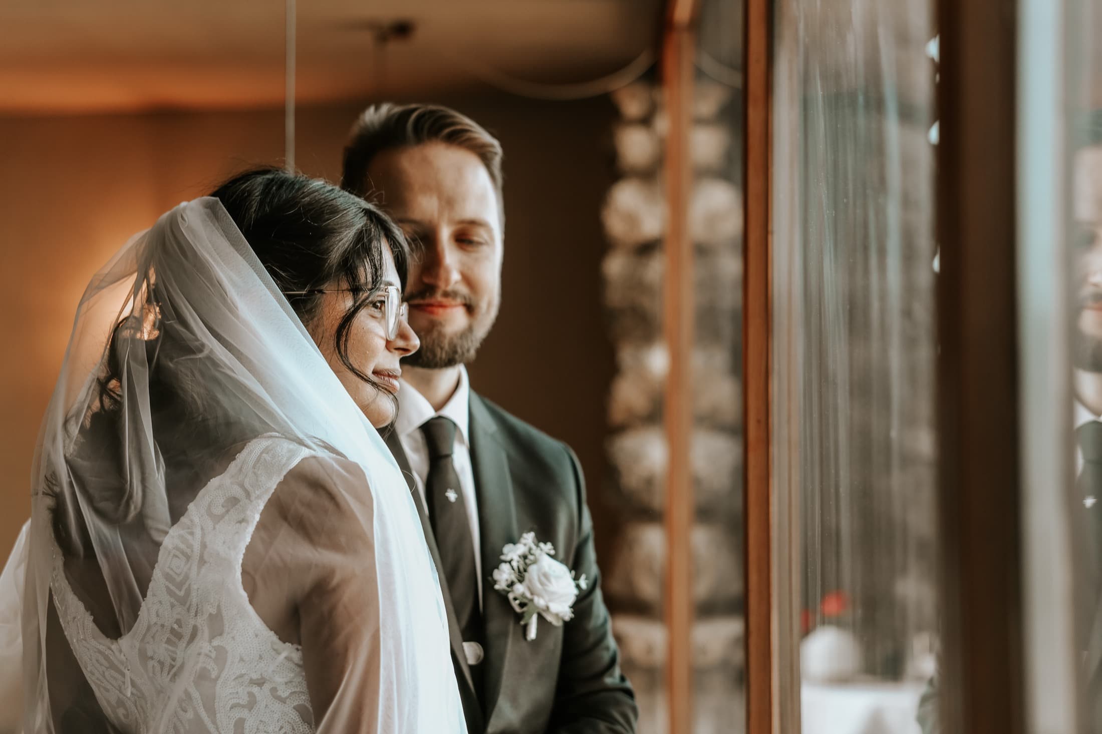 Bride and groom sharing a quiet look by a window