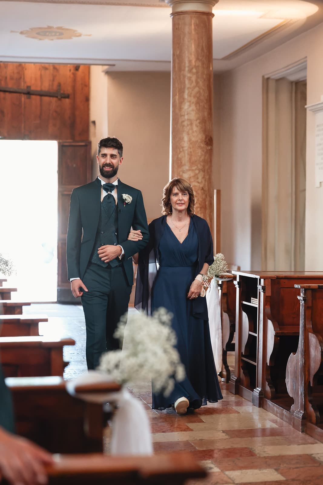 Groom walking down the aisle with his mother