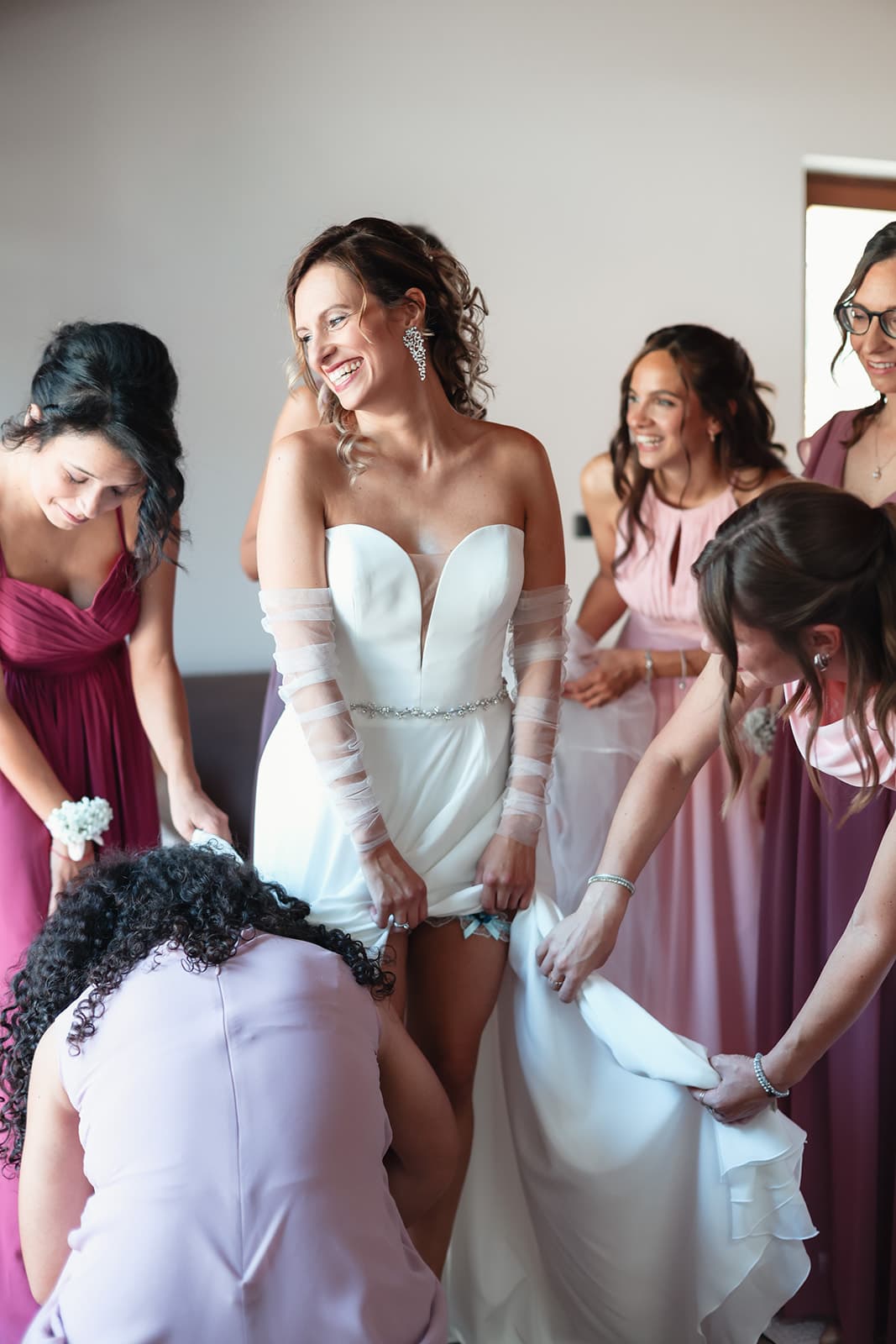 Bridesmaids helping the bride into her dress